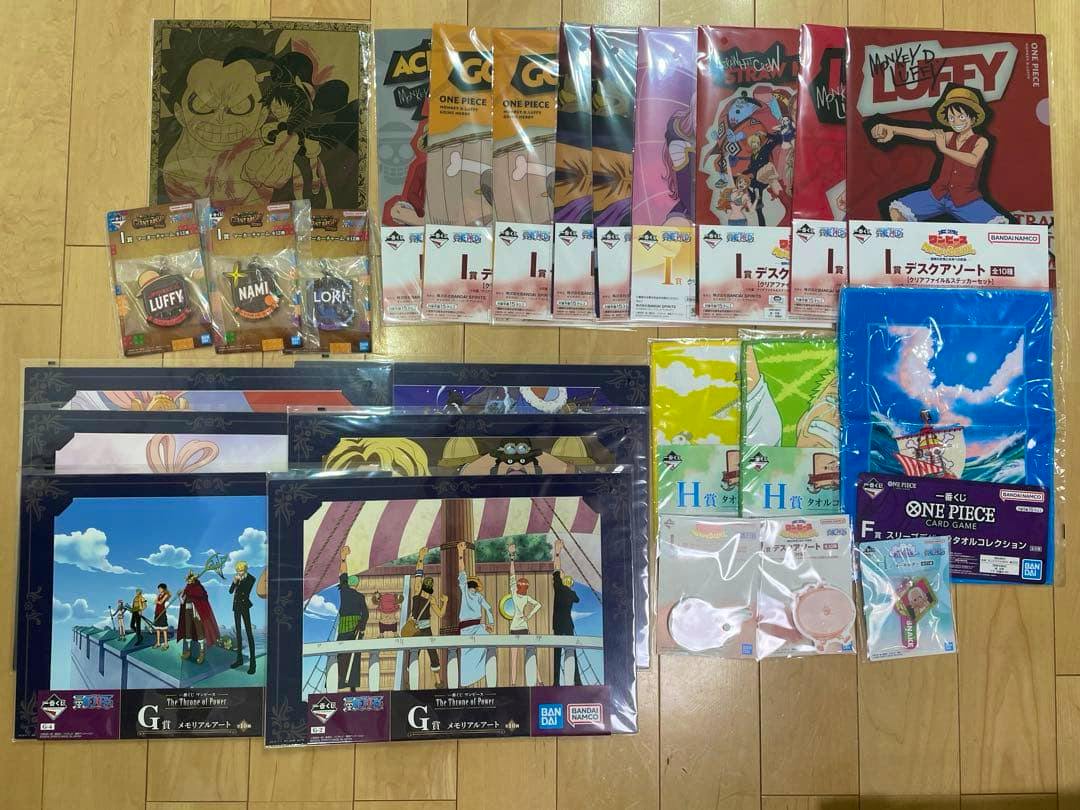Multiple sealed One Piece clear file folders and prize items arranged on a wooden floor.