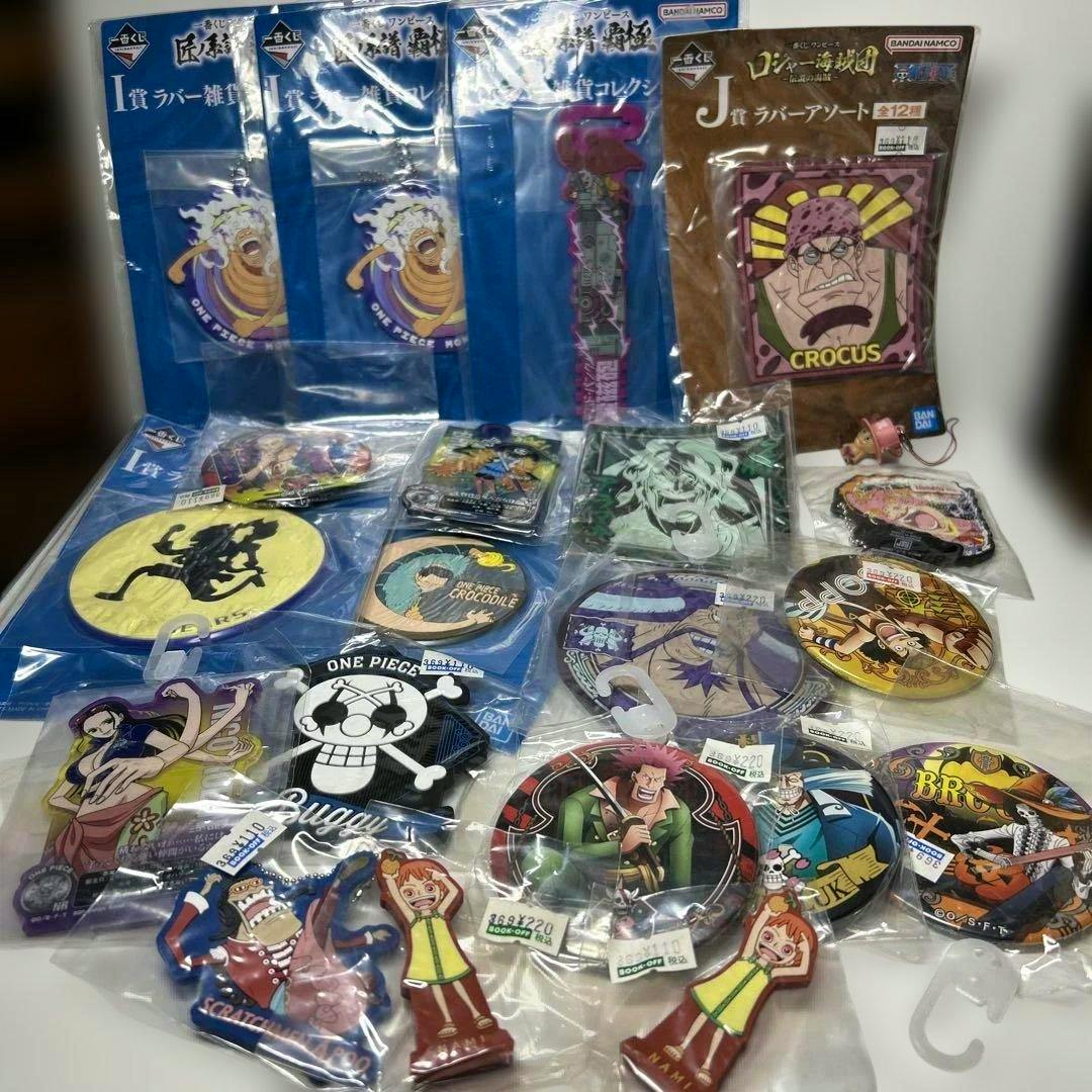A spread of One Piece rubber keychains and rubber goods in their packaging arranged on a table.