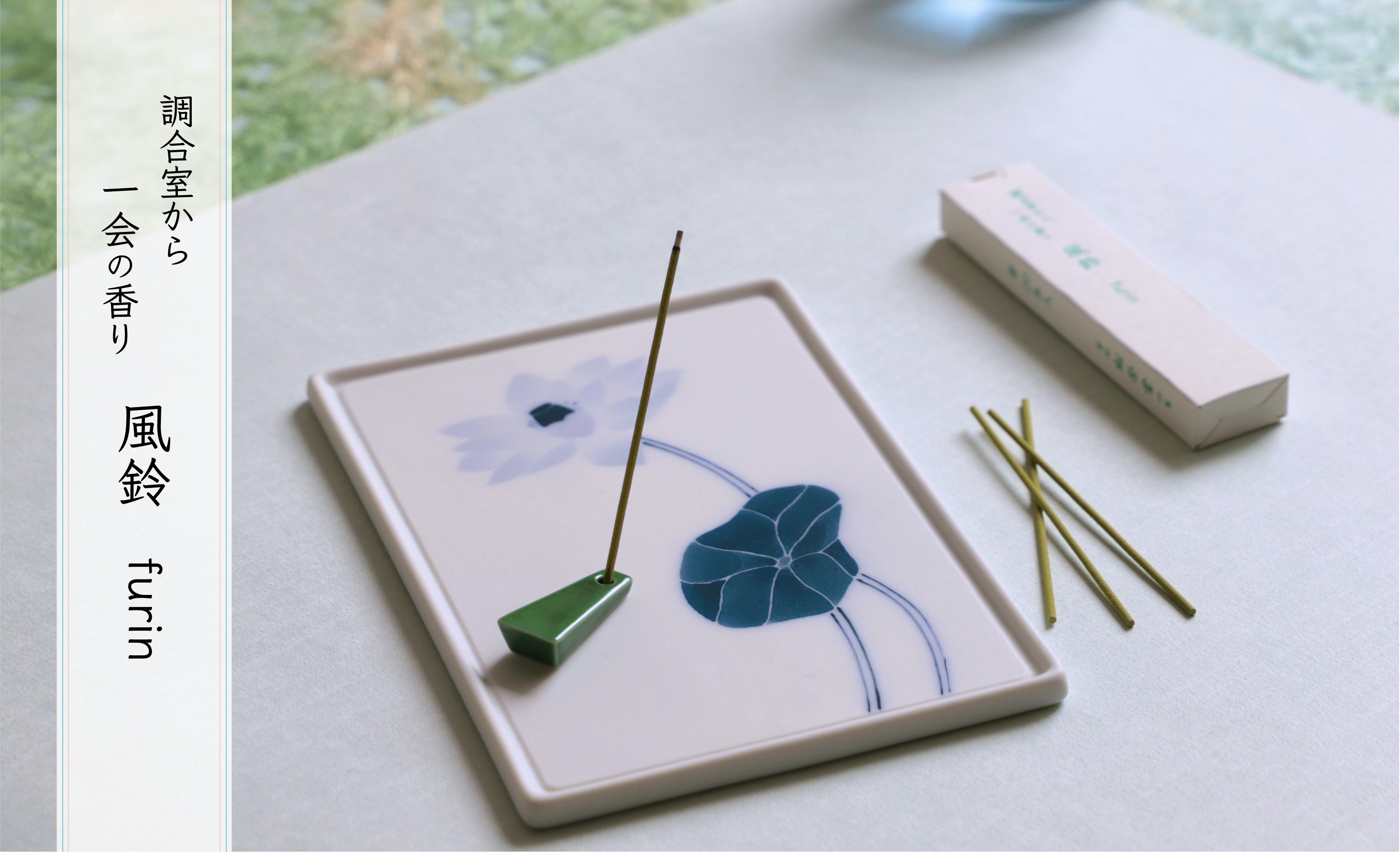 Thin incense sticks with a green ceramic incense holder placed on a decorative ceramic tray and the incense box nearby.