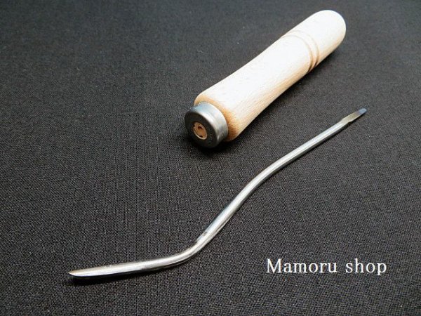 Wooden-handled chisel with a curved metal blade lying on a black surface.
