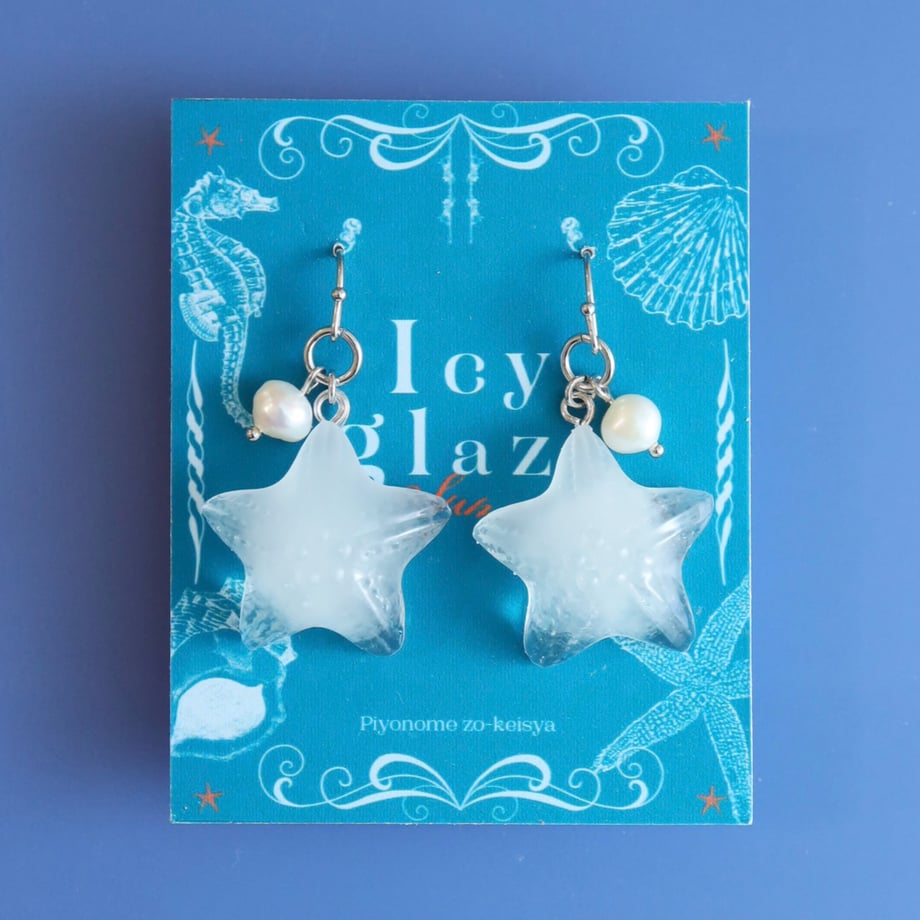 Translucent star-shaped earrings with small pearl beads displayed on a blue 'Icy glaze' backing card.