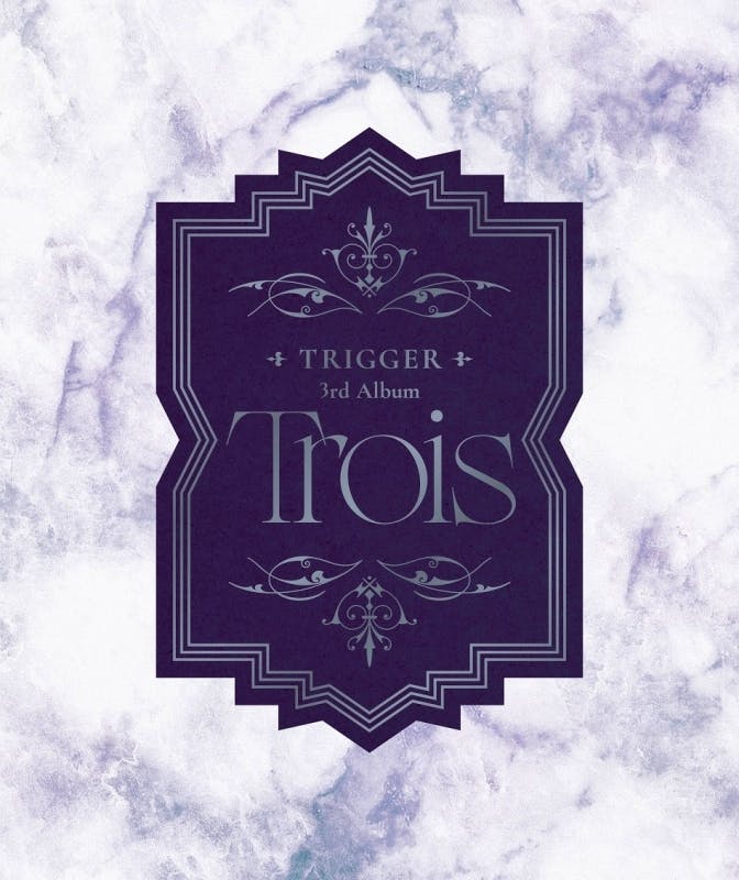 Cover artwork for TRIGGER 3rd Album "Trois" showing a purple ornamental label on a marbled background.