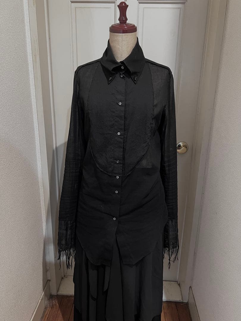 Front view of a black men's silk shirt on a mannequin with a buttoned front and long fringed sleeves.