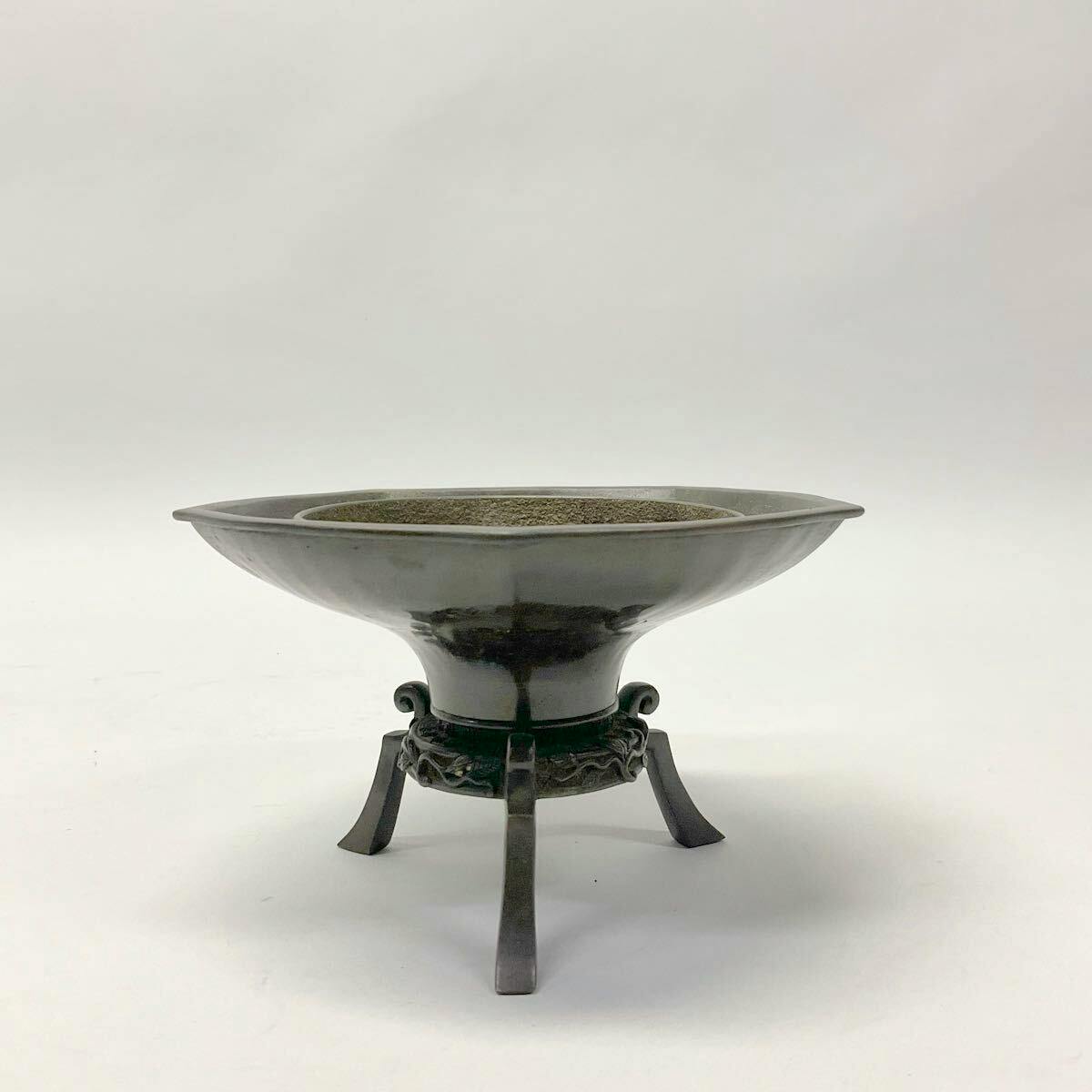 A three-legged ikebana flower vessel with a wide shallow bowl mounted on a tripod stand, shown on a white background.