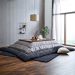 Rectangular black shijira-weave kotatsu futon draped around a low wooden heated table in a bright room.