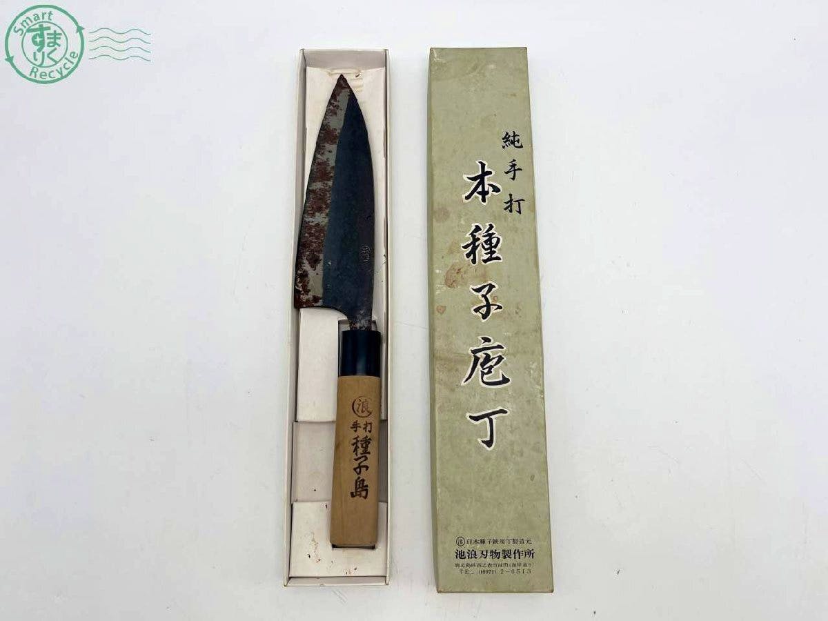 Used chef knife with a wooden handle and a rusted blade displayed inside its box next to the cardboard outer box with Japanese text.