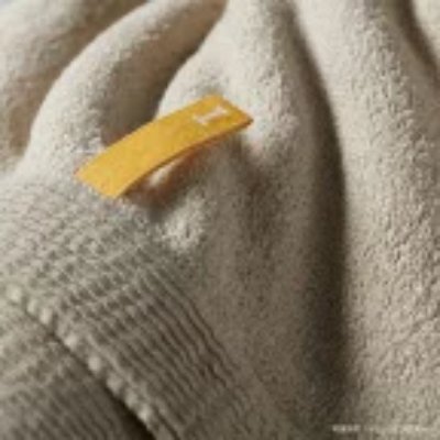 Close-up of a face towel's textured organic cotton fabric with a small yellow tag.