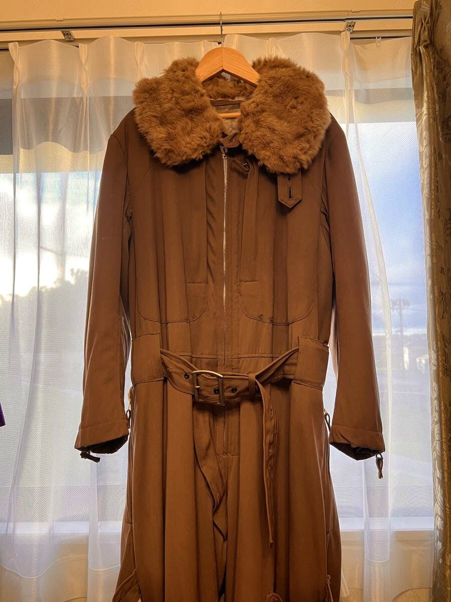 Brown cotton woven men's WWII Imperial Japanese Army winter electric flight jacket with a fur collar hanging on a wooden hanger in front of a window.
