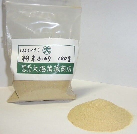 Clear plastic bag of industrial seaweed powder labeled 100g with a small pile of powder on a white surface.