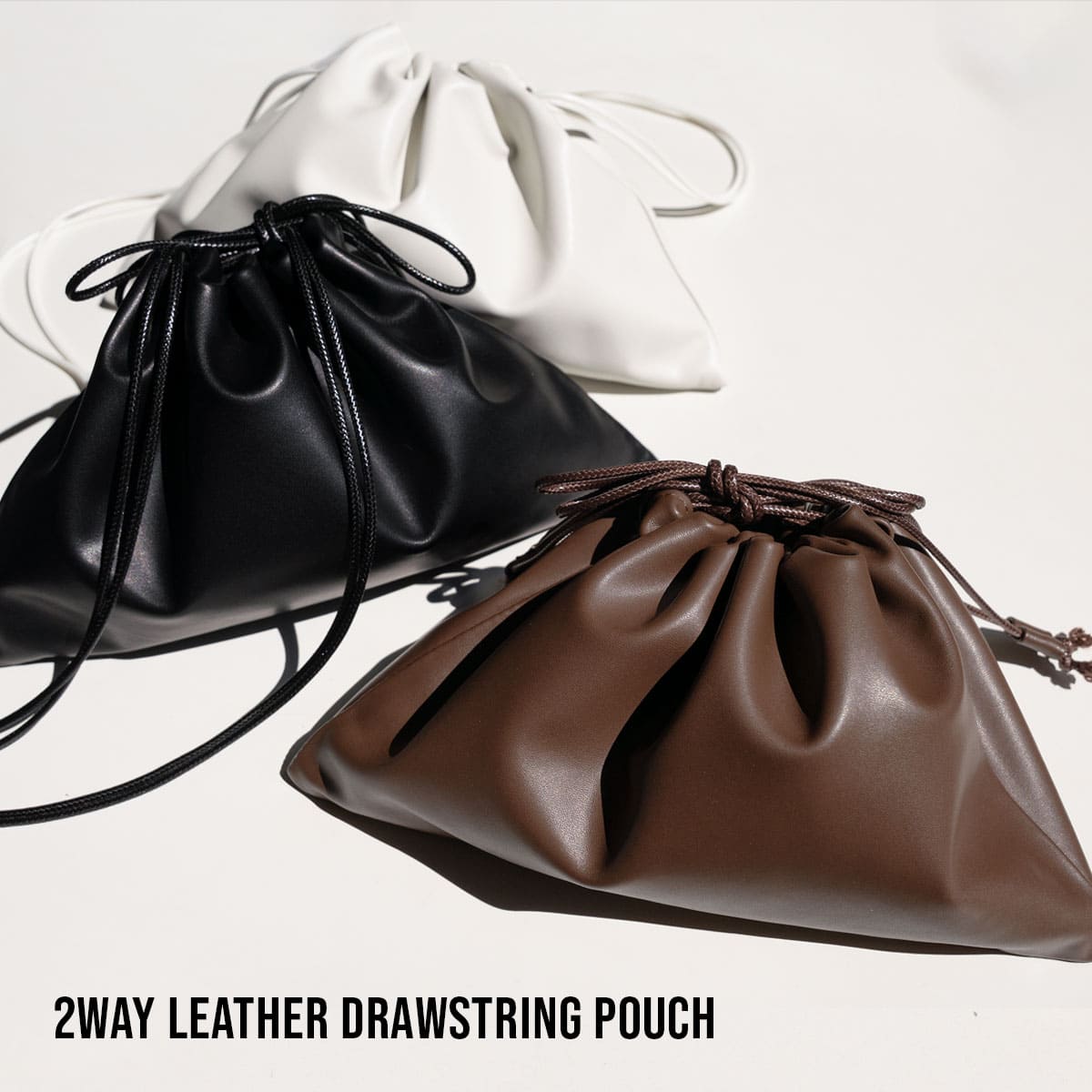 Three small drawstring cow leather pouch bags in white, black, and brown arranged together.