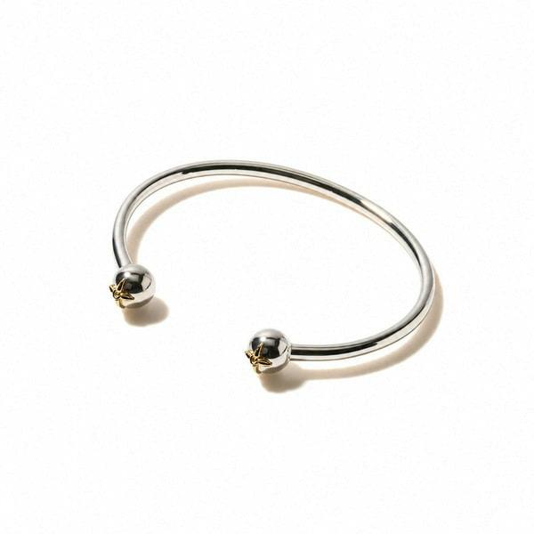 An open bi-color bangle with spherical end caps displayed on a white background.