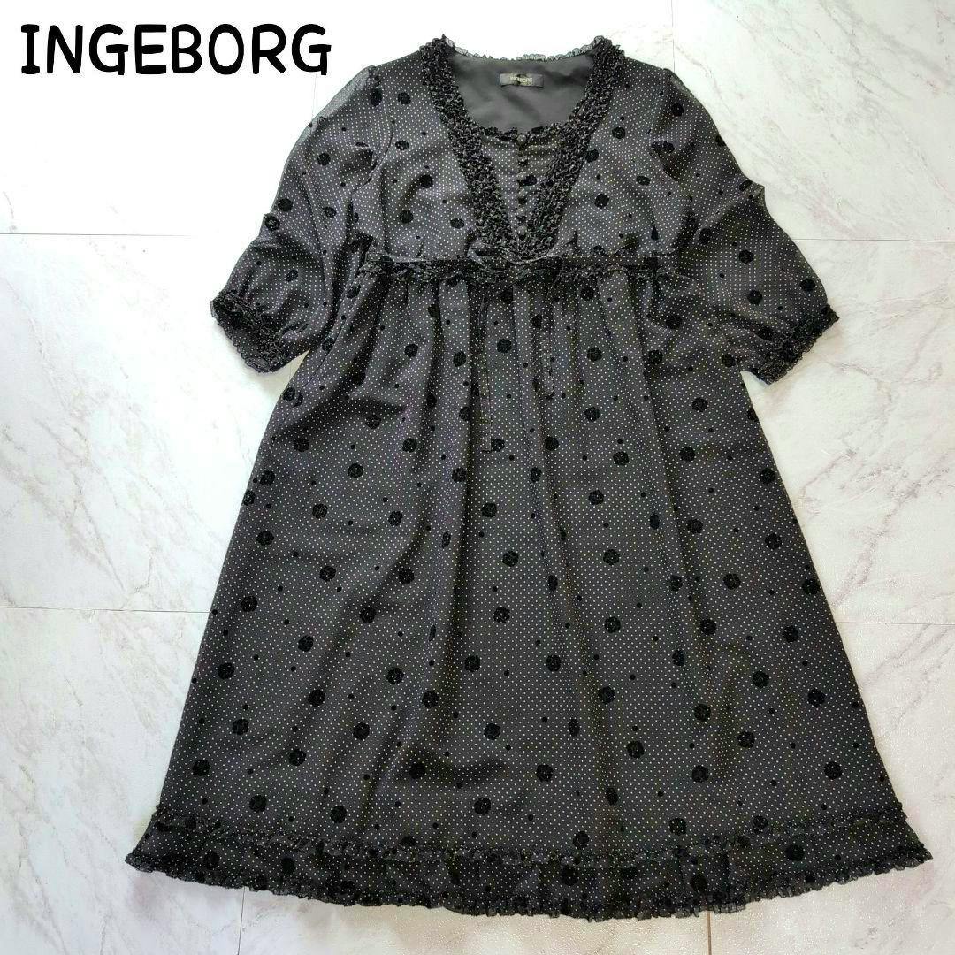 Front view of a dotted dress with sheer three-quarter sleeves and lace trim laid flat on a floor.