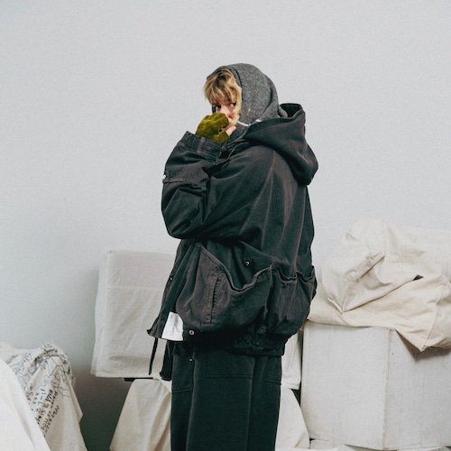 Model wearing the dark Sumikuro HUNTER HIKER women's cotton jacket with hood, shown in side profile.