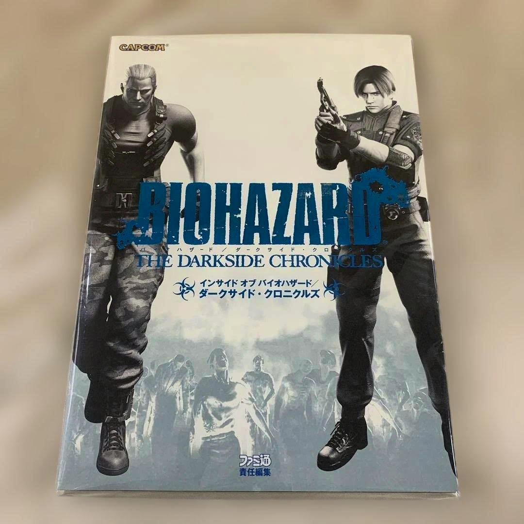 Front cover of the book showing the title "BIOHAZARD THE DARKSIDE CHRONICLES" with two armed characters and zombies in the background.