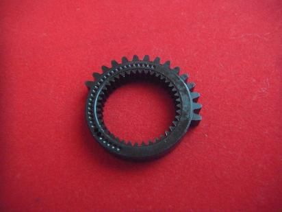 An internal sector gear for a toy airsoft gun photographed on a red background.
