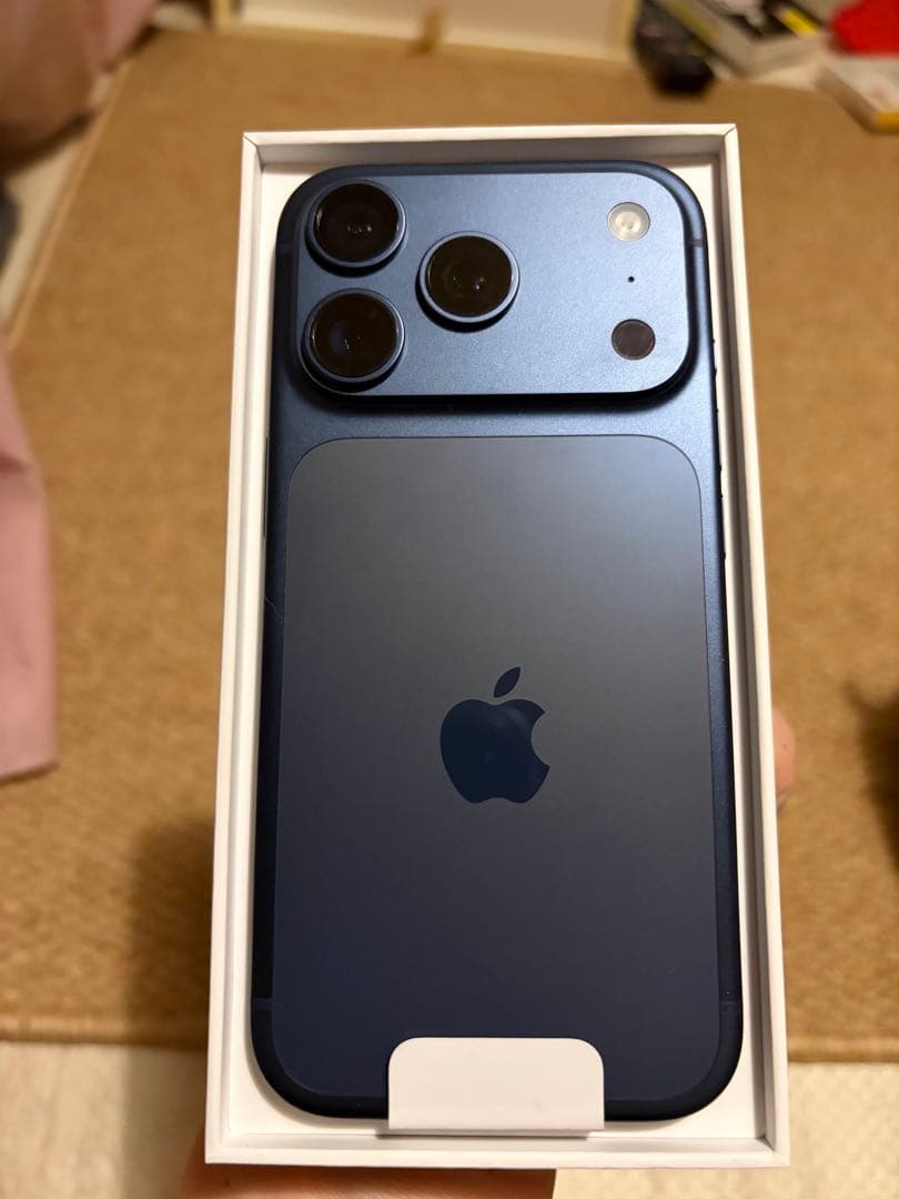 Back of an iPhone 17 Pro in Deep Blue shown inside its retail box.