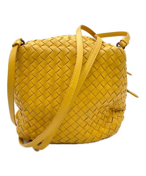 Yellow intrecciato cow leather shoulder bag with a long strap on a white background.