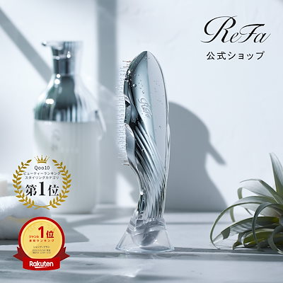 A silver ion-care hair brush standing upright on a clear stand with its bristles visible in a bright tabletop setting.