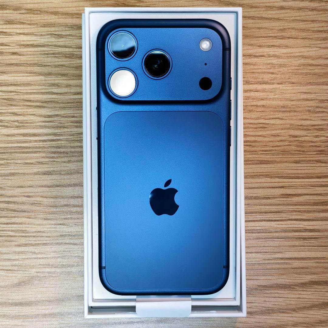 Deep-blue iPhone 17 Pro shown from the back in its box on a wooden surface.