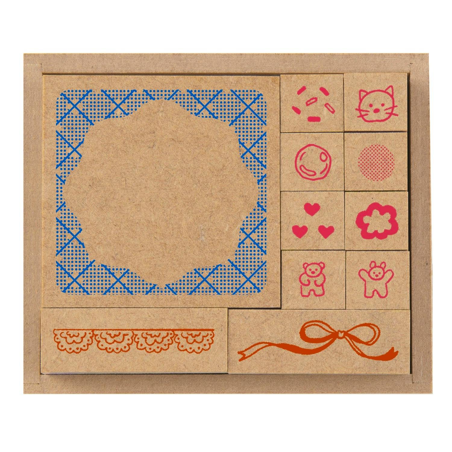 Close-up of the wooden no-ink stamp set in its box showing a large decorative stamp and several small wooden stamps with icons (cat, hearts, bear), a lace border, and a ribbon design.