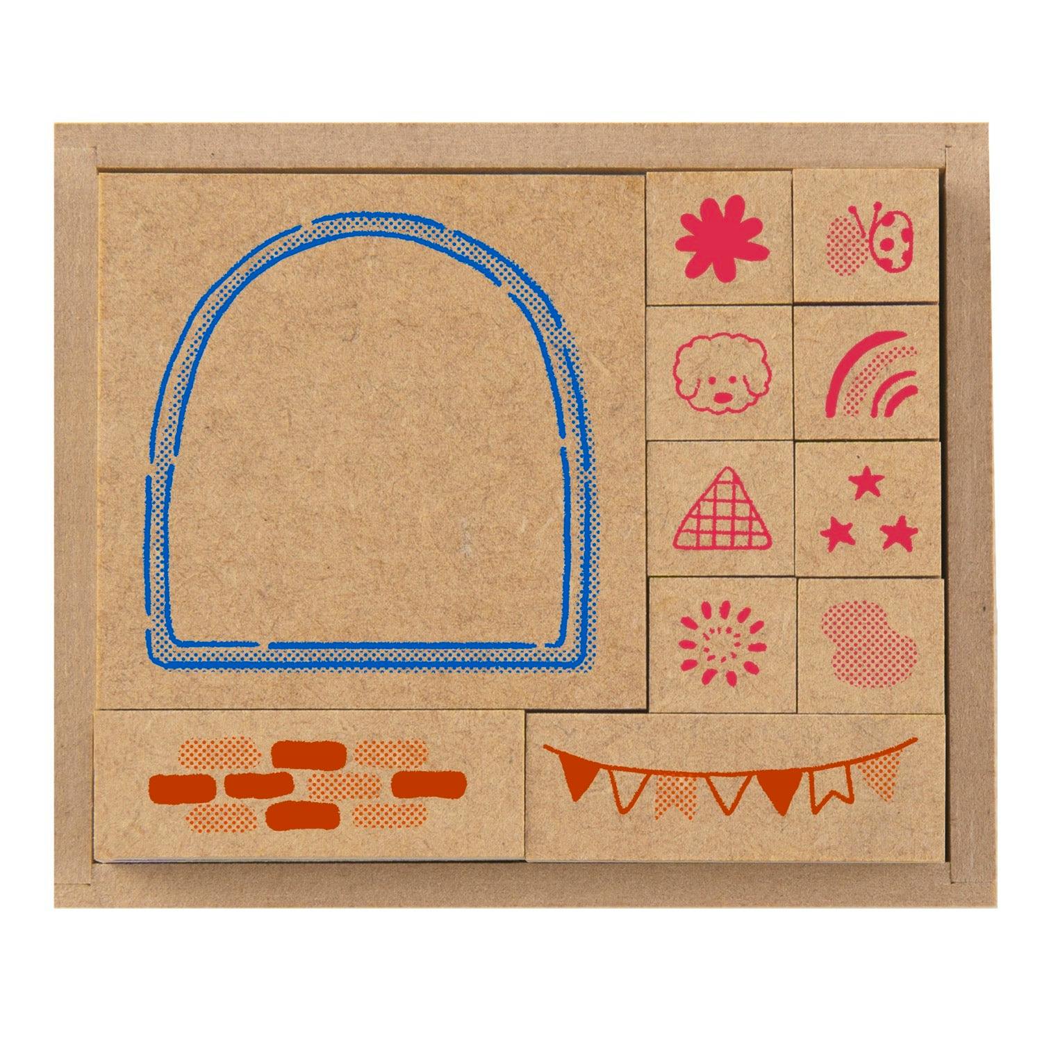 Top-down photo of the wooden stamp set in its box showing multiple small square wooden stamps and printed motif samples on the wood.