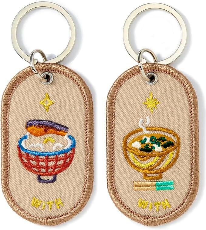 Close-up of two embroidered fabric keychain patches attached to metal rings, each showing a bowl design.