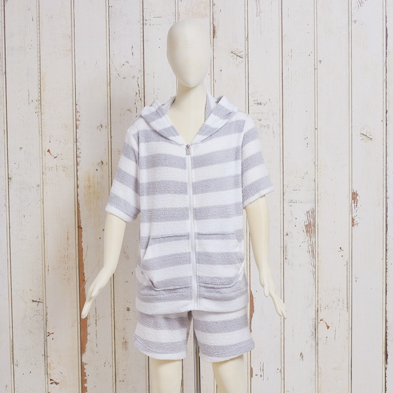 Mannequin wearing a men's short-sleeve gray-and-white striped zip-up pajama top with hood and front pockets.