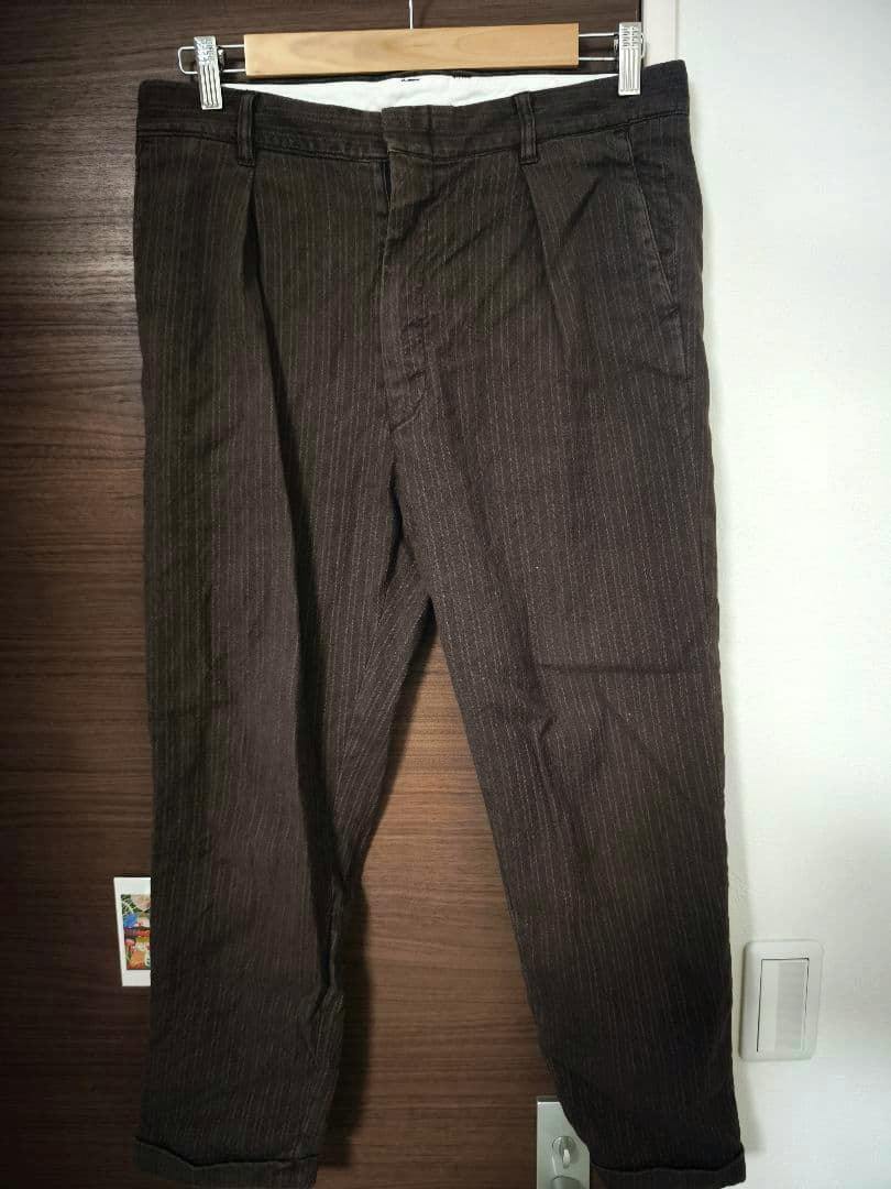 Front view of ISAMU KATAYAMA BACKLASH men's cotton striped pants hanging on a wooden hanger.
