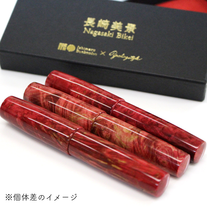 Three red glass fountain pens with a swirling marbled pattern are displayed in front of a black presentation box labeled "Nagasaki Bikai".
