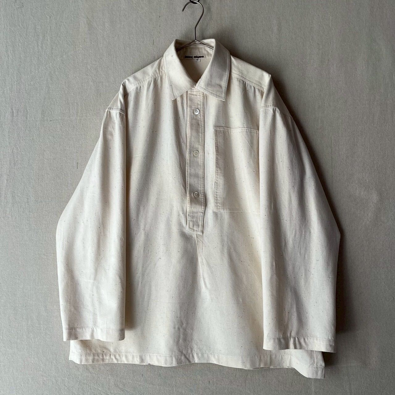 Ivory women's pullover cotton shirt hanging on a hanger against a neutral background.