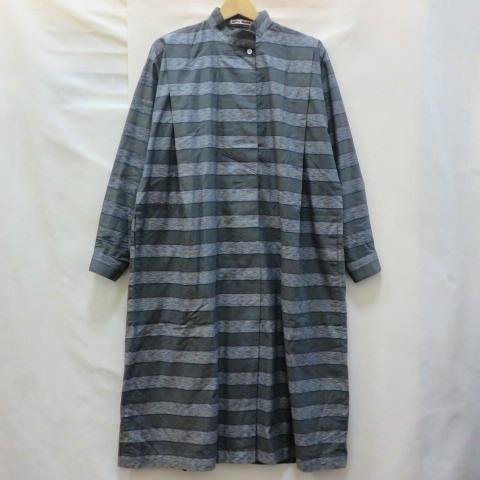 Front view of a gray striped long-sleeve stand-collar Issey Miyake one-piece shirt hanging on a hanger against a white background.