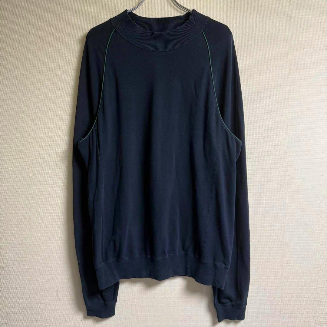 Issey Miyake MEN raglan sweatshirt hanging on a hanger against a plain wall, front view.