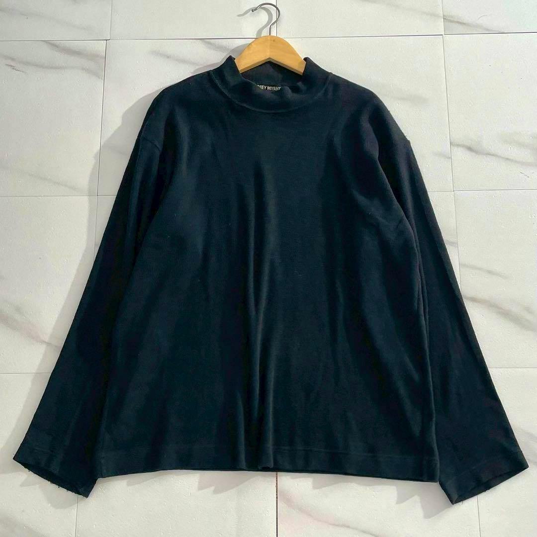 Front view of a black men's long-sleeve cotton cut-and-sewn pile shirt by ISSEY MIYAKE hanging on a wooden hanger against a tiled background.