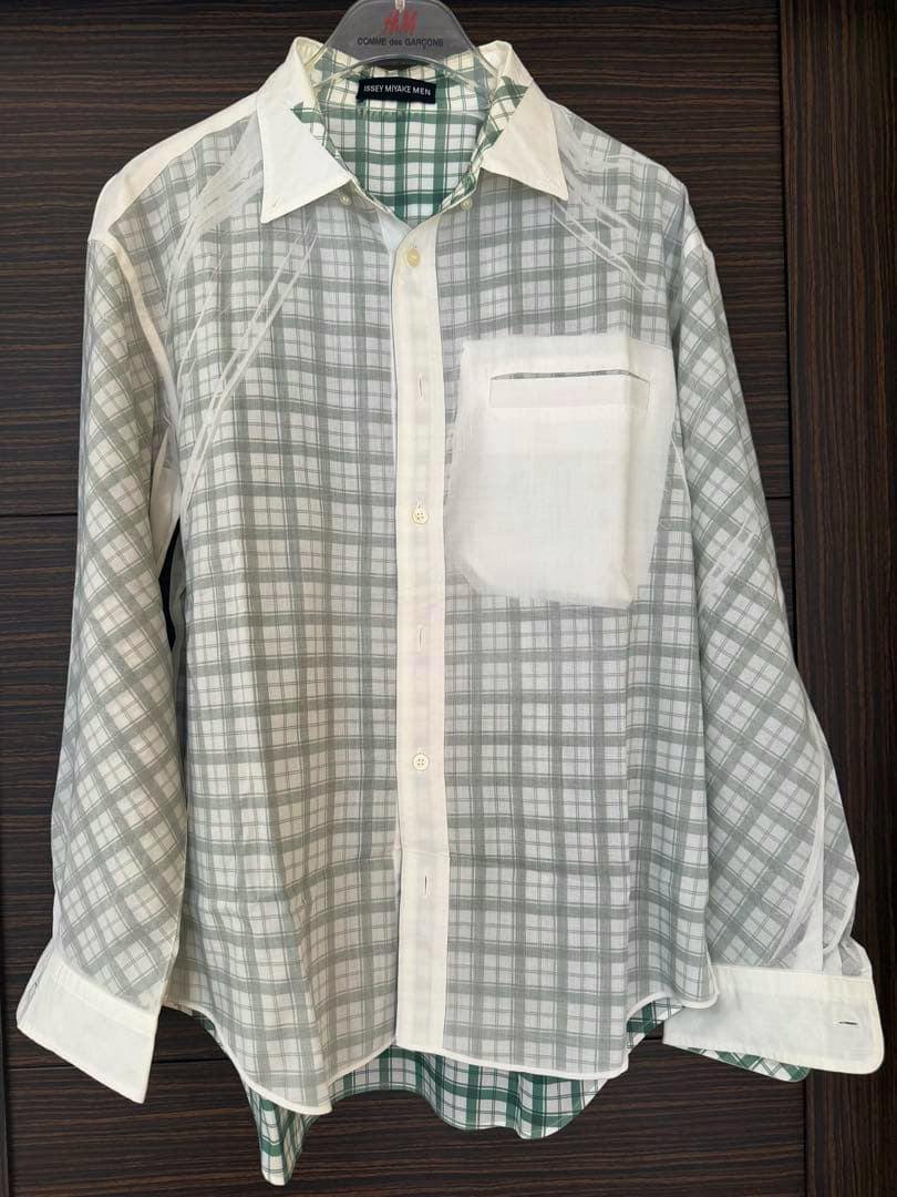 Front view of an ISSEY MIYAKE MEN check-pattern men's shirt hanging on a hanger, showing the full front and chest pocket.