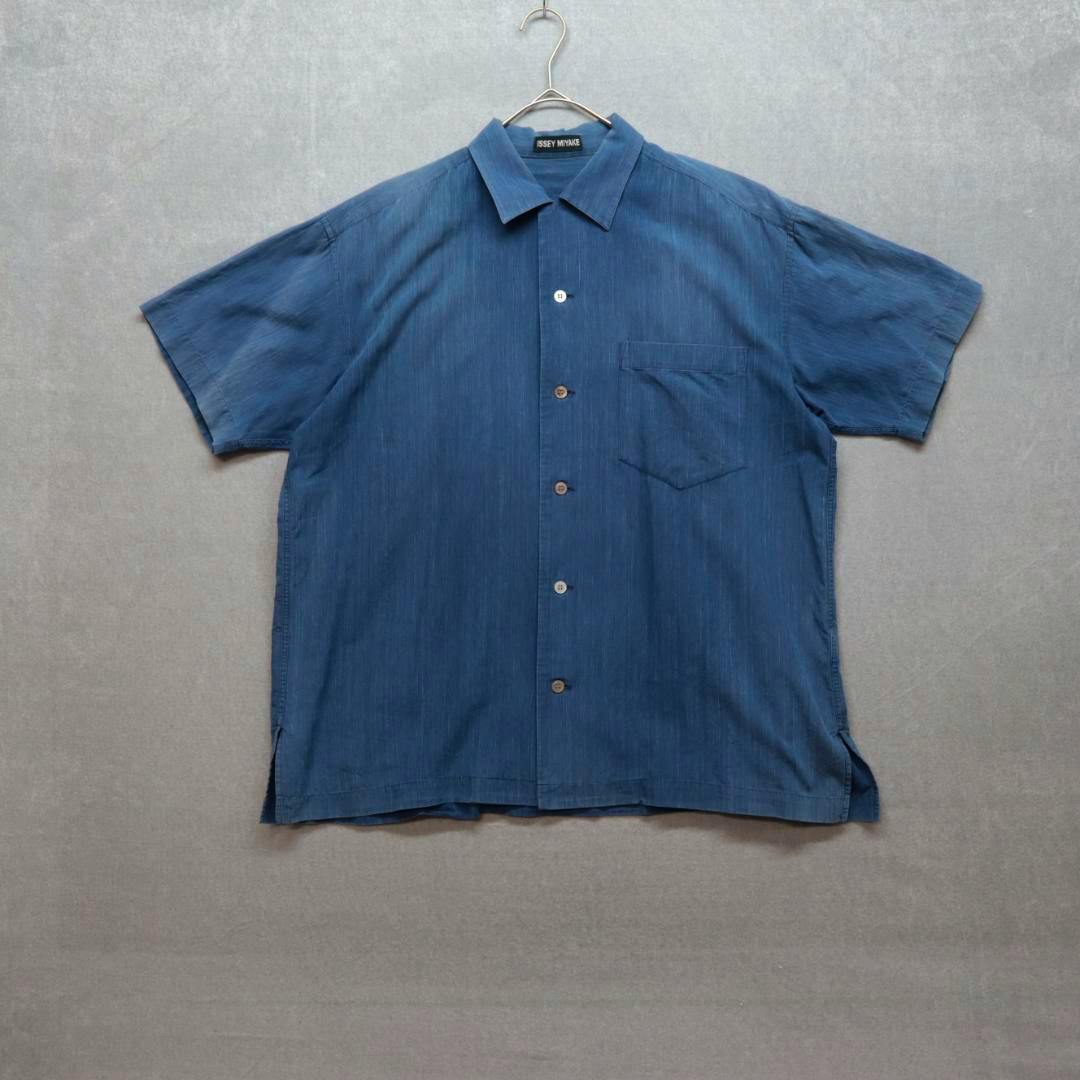 Blue short-sleeve open-collar men's shirt hanging on a hanger against a gray background.