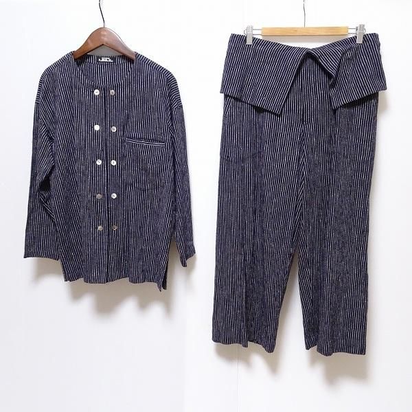 Navy and white striped men's cotton shirt hanging beside matching pants on hangers against a white background.