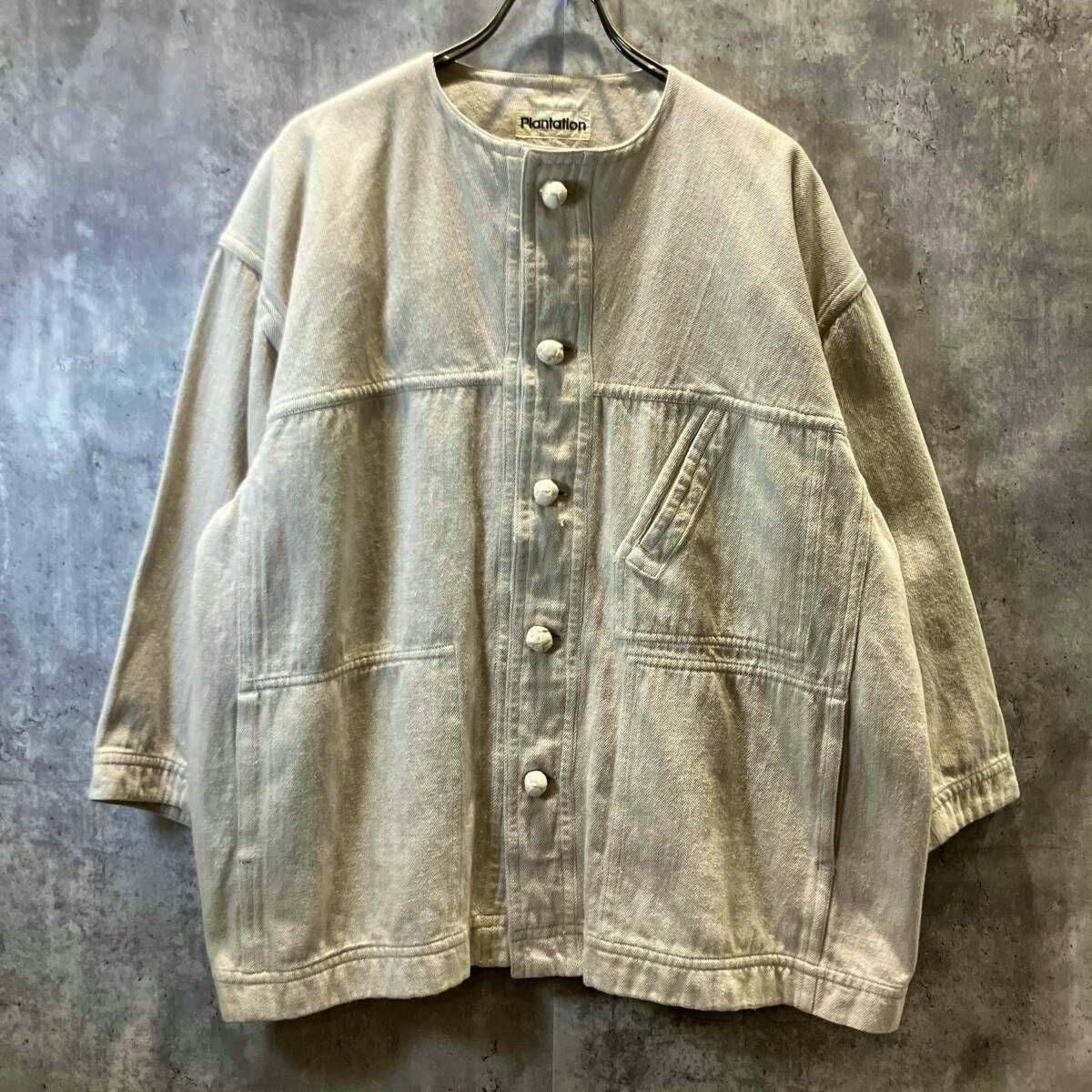 Ivory ISSEY MIYAKE Plantation no-collar cotton women's jacket hanging on a hanger, front view with buttons visible.
