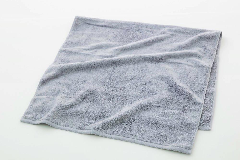 A gray cotton bath towel laid flat with gentle folds on a white background.