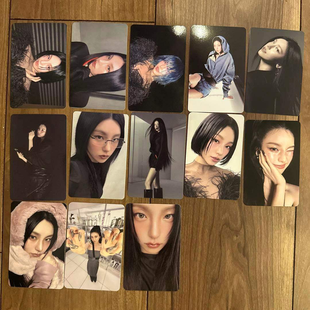 Several ITZY "Air" album photocards arranged on a wooden floor.