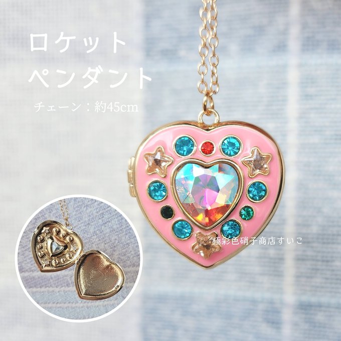 Front view of a pink heart-shaped pendant locket with an iridescent heart-shaped central gem, blue and red rhinestones, star decorations, and a gold-tone chain.