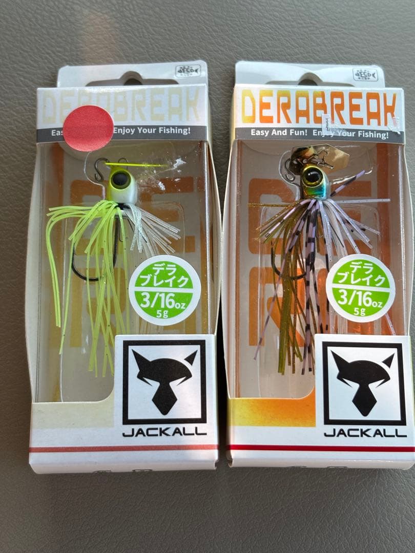 Front view of two Jackall Dera Break 3/16 oz fishing lures in retail packaging shown side by side.