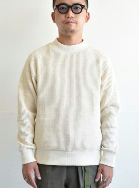 Front view of a person wearing a cream waffle-knit mid-neck cotton long-sleeve sweater.