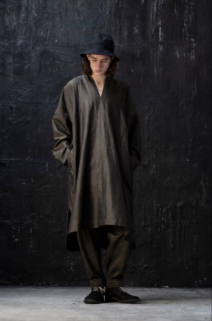 Model wearing a long wool tunic-style women's shirt with long sleeves and a V-neck, photographed against a dark textured background.
