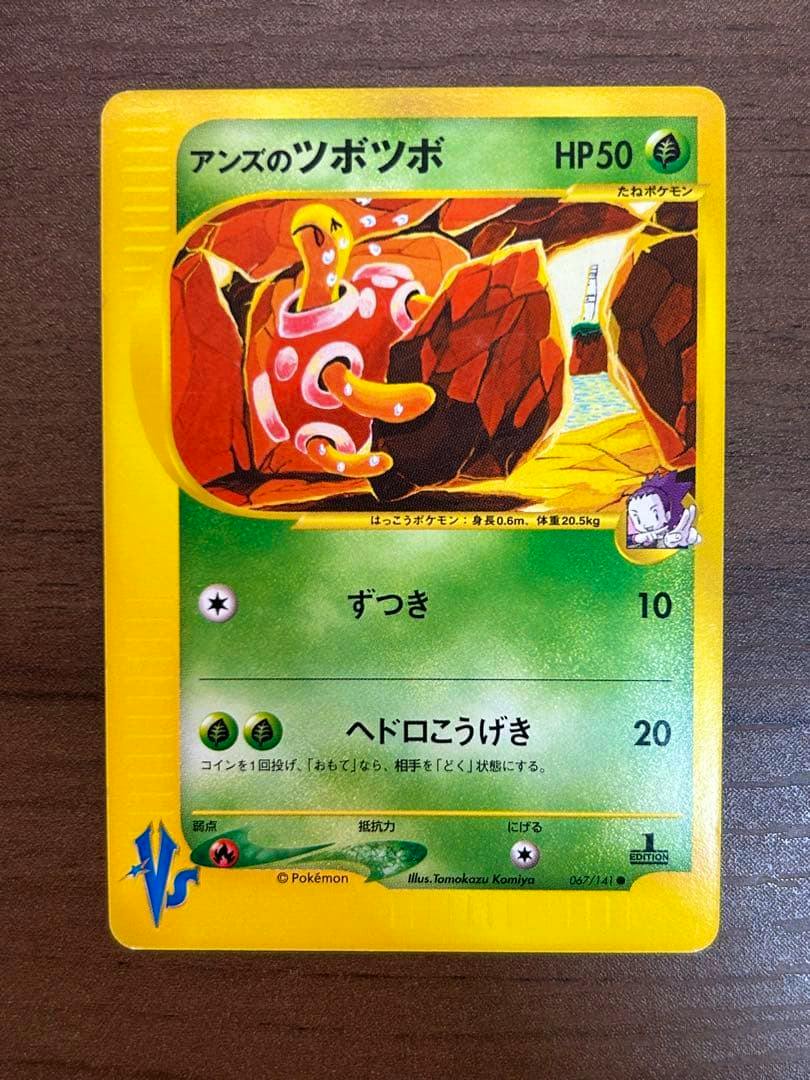 Front of the trading card アンズのツボツボ ● ポケモンカード★VS 067/141 on a wood-textured surface, showing the artwork, HP50, attacks, and yellow border.