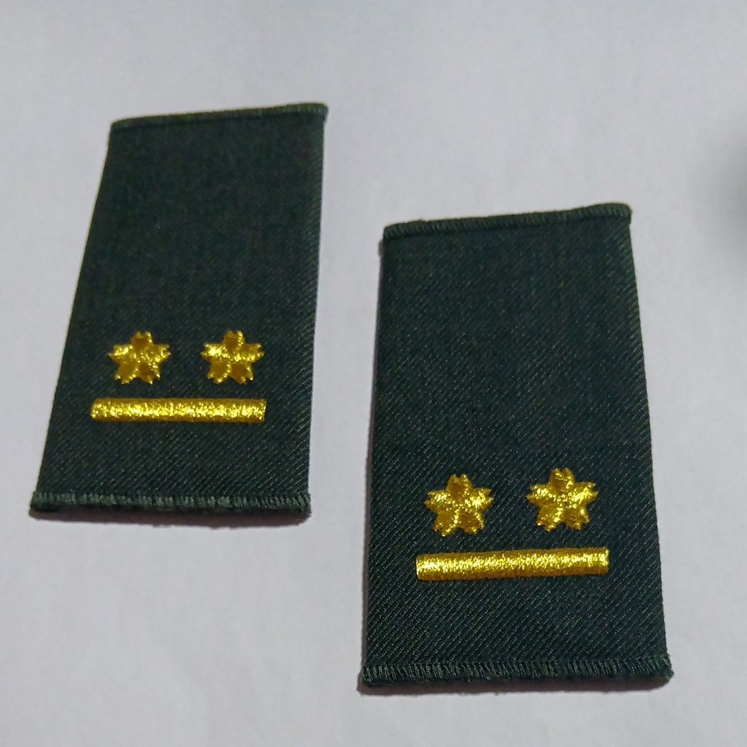 Two green fabric rank patches for the Japan Ground Self-Defense Force showing two gold stars and a gold bar on a white background.