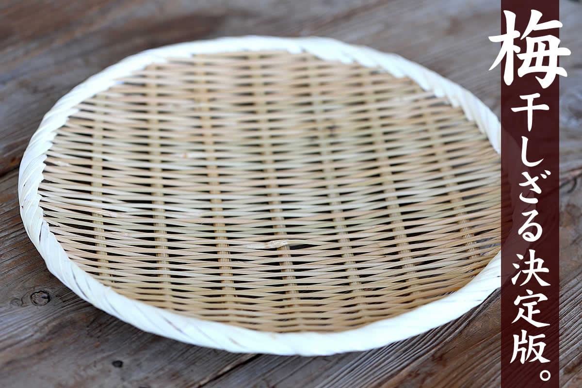 A round bamboo zaru (27cm) laid on a wooden surface showing its woven surface and white rim.