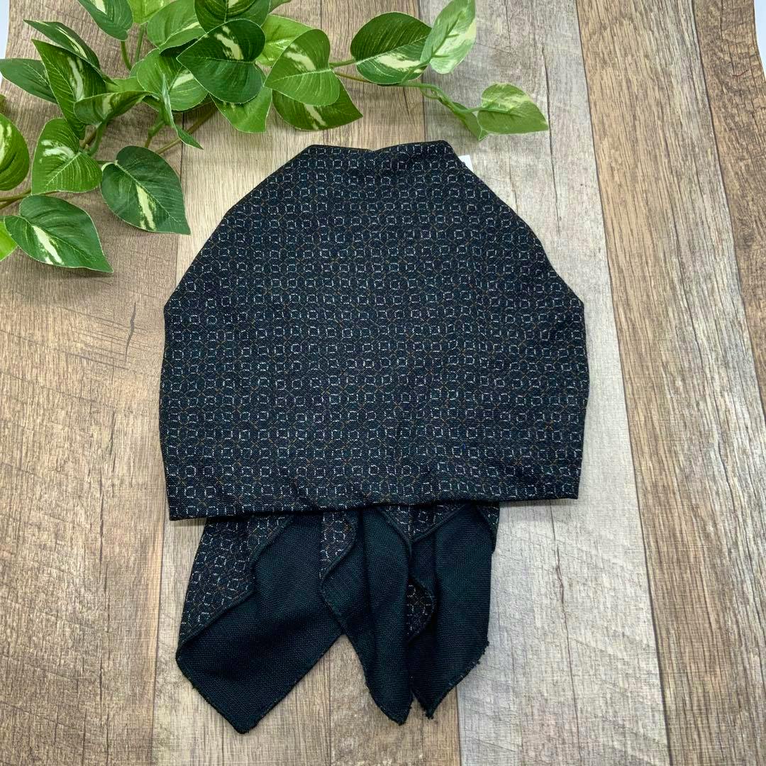 A black patterned cotton bandana cap laid flat on a wooden surface with its ties visible.