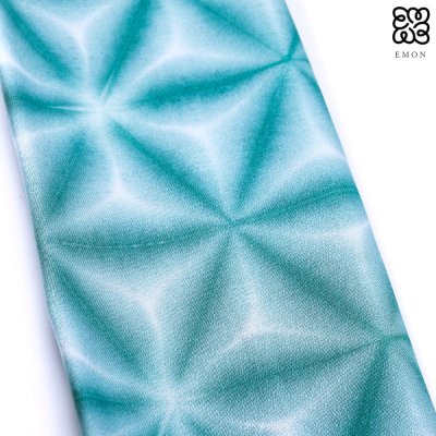 Close-up of a green patterned silk obi for kimono showing a shibori snowflake design.