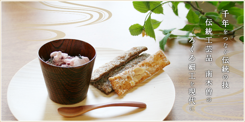 Wooden bowl shown holding a scoop of ice cream on a round plate with a wooden spoon and pastries.