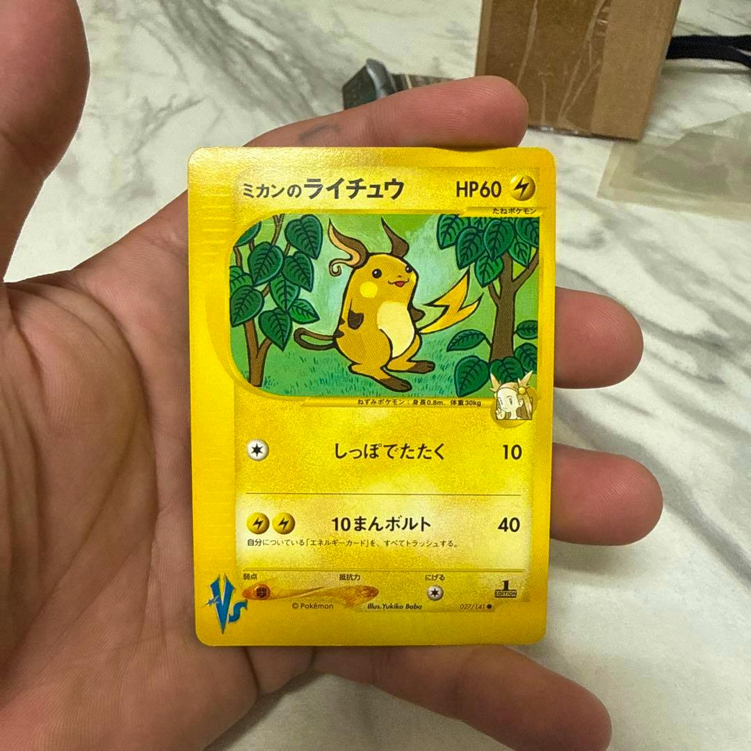 Front of the ミカンのライチュウ Pokémon trading card showing Raichu artwork held in a hand.